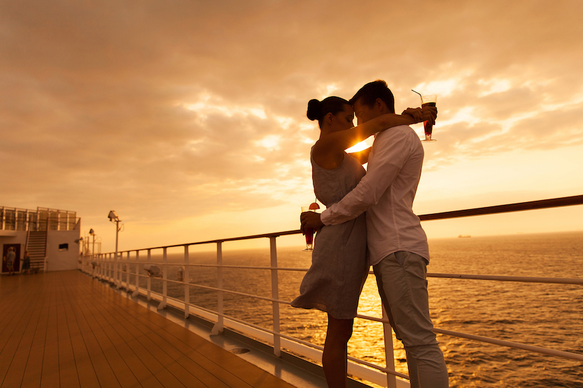 romantic couple hugging with eyes closed at sunset on a cruise ship